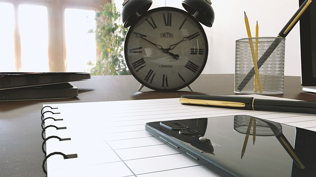 Photo of a clock and a phone on a desk.